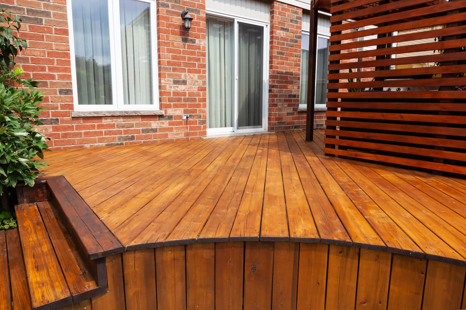 Backyard deck with steps and privacy screen freshly stained in warm cedar tone next to a brick home in Dallas, Texas
