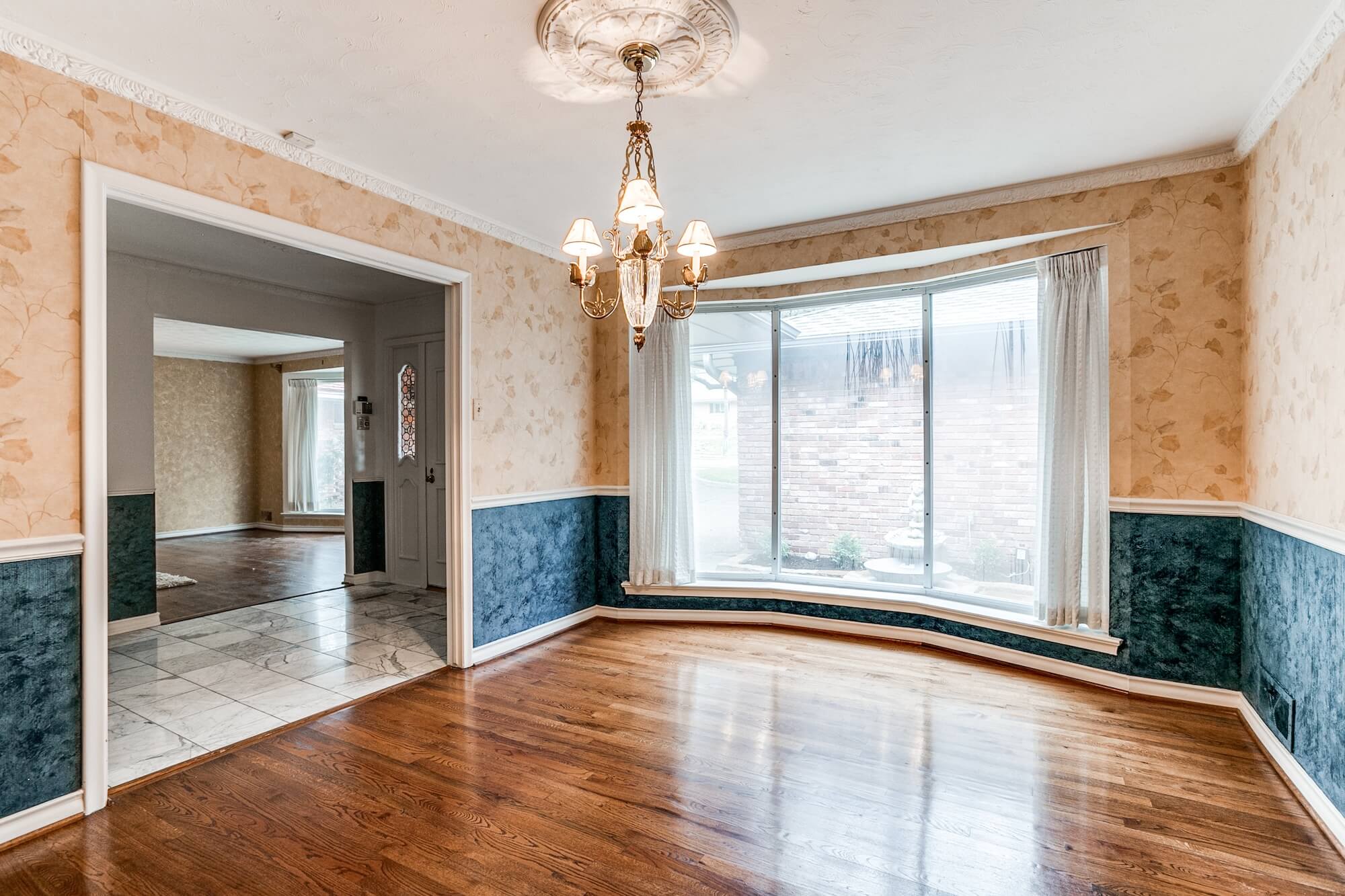 Dining room with bay window, hardwood floors and navy painted wainscoting, an interior painting project by San Miguel Painting in Dallas, Texas