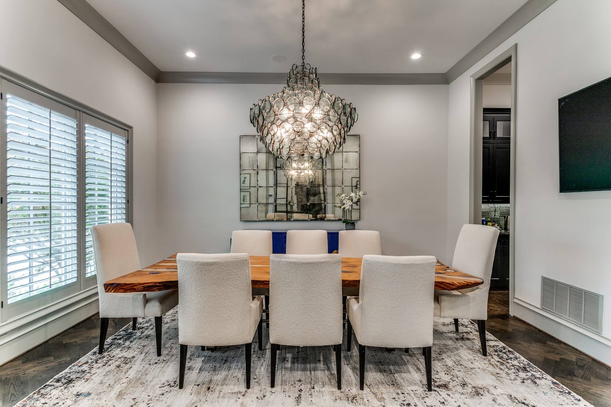 Formal dining room with soft gray walls, white crown molding and plantation shutters painted by San Miguel Painting in Dallas, Texas