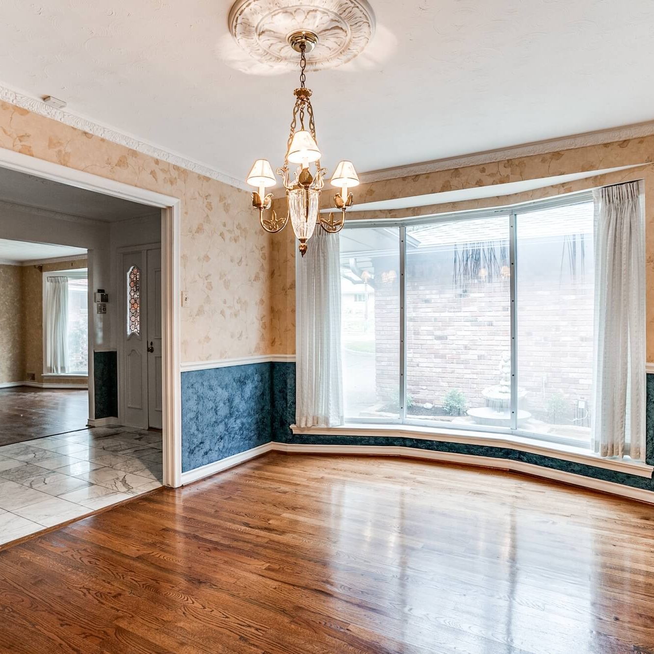 Dining room with bay window, hardwood floors and navy painted wainscoting, an interior painting project by San Miguel Painting in Dallas, Texas